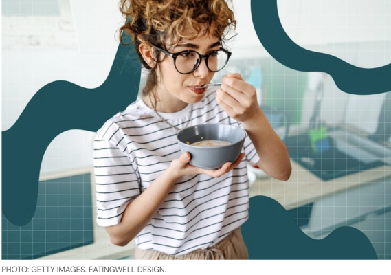 Woman with glasses and striped shirt eating bowl of cereal standing
