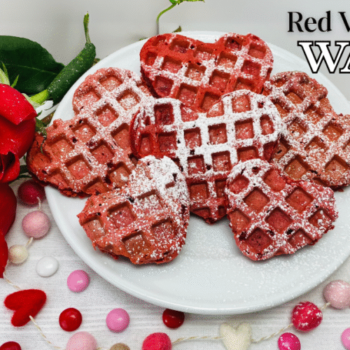 Red velvet Belgian waffles in heart shapes feature image next to red roses