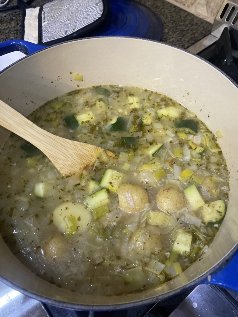 potatoes, zucchini & herbs in bowl cooking.