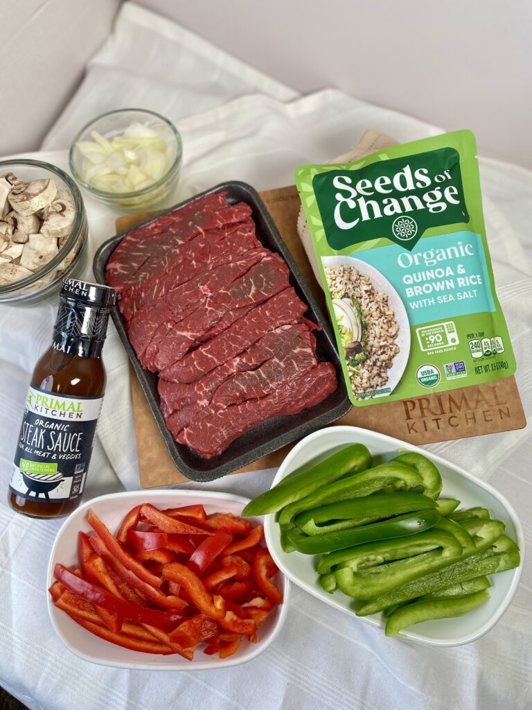 steak fajita recipe individual ingredients including fajita strips, red and green sliced bell peppers, steak sauce and onions