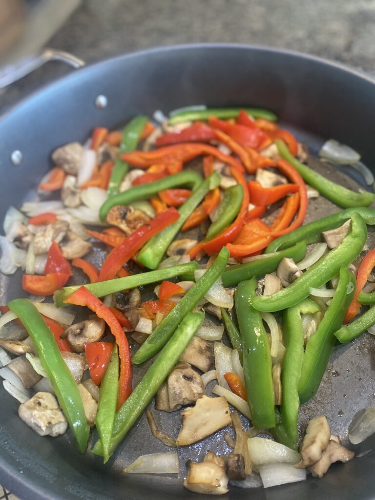 bell peppers, mushrooms and onions sautéing in electric grill pan